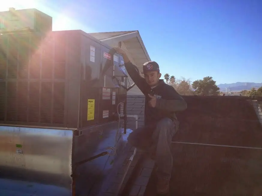 HVAC technician performing AC Tune-Up on a rooftop unit in Leoni