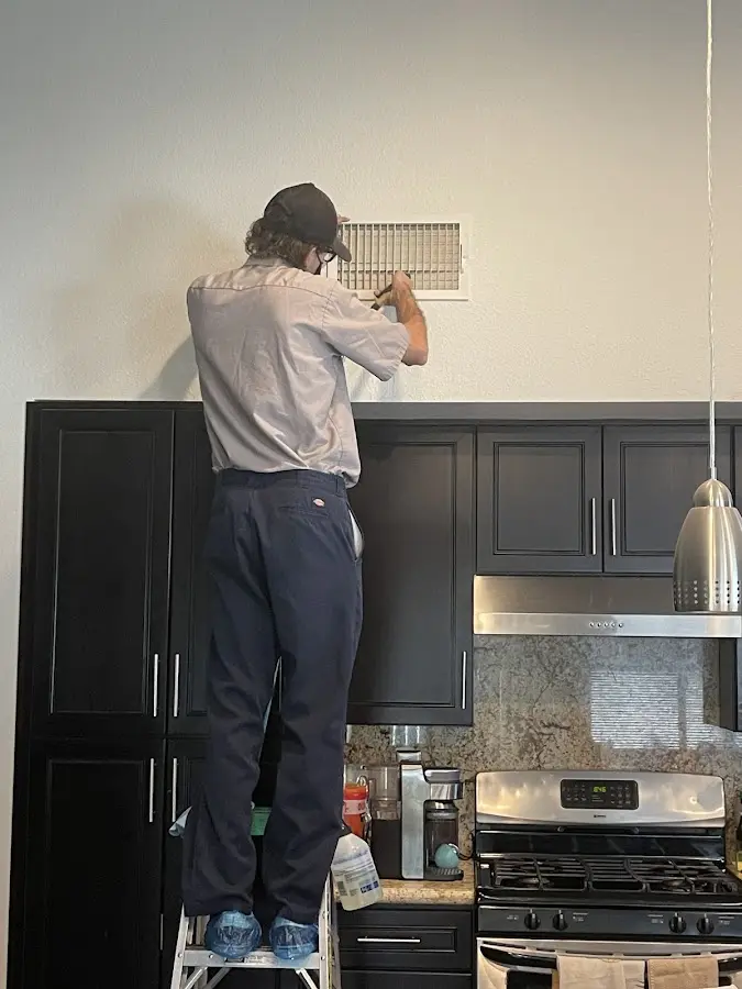 Technician inspecting an air vent during HVAC service in Leoni
